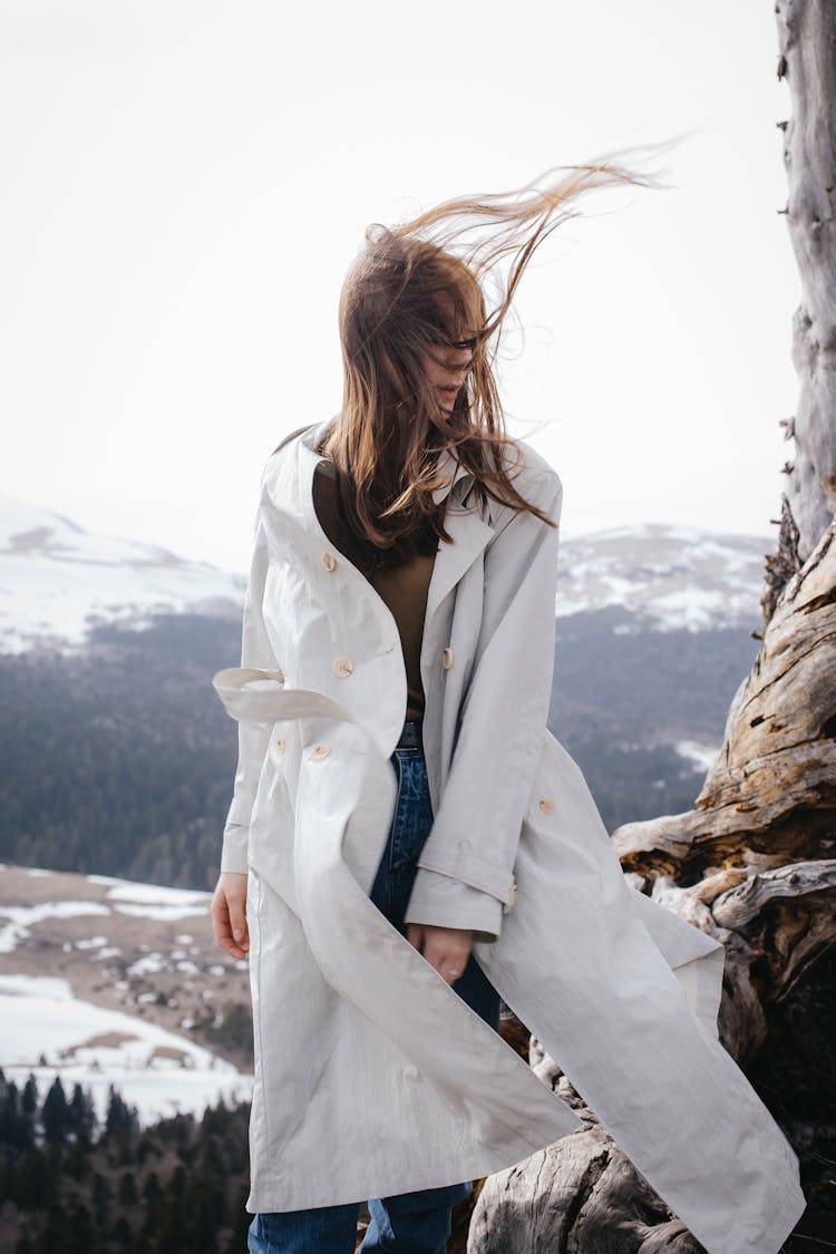 Woman In White Trench Coat With Windswept Hair In Landscape