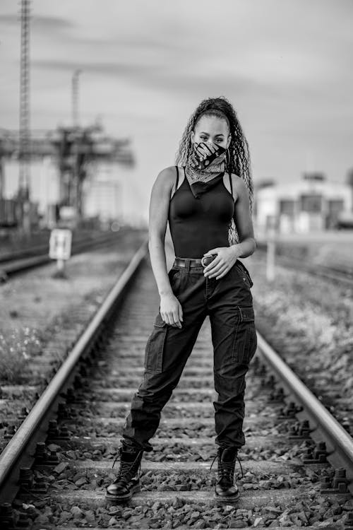 Woman in Tank Top and Denim Jeans Standing on Train Rail