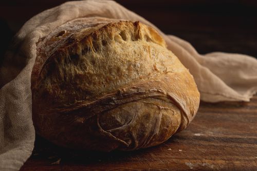 Free Close-up of a freshly baked artisanal sourdough bread on a wooden surface with a linen cloth. Stock Photo