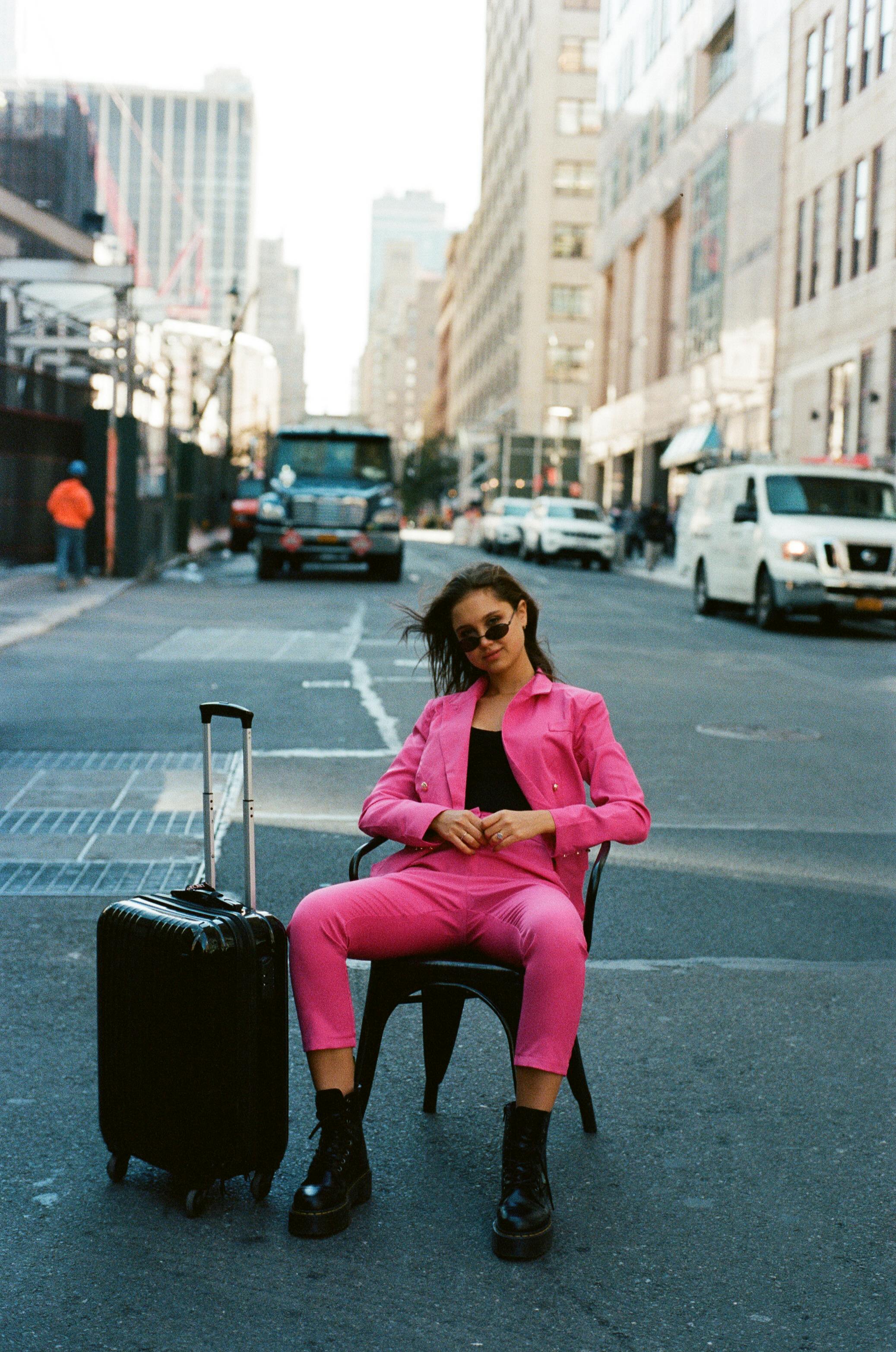 woman in pink suit sitting on chair on street