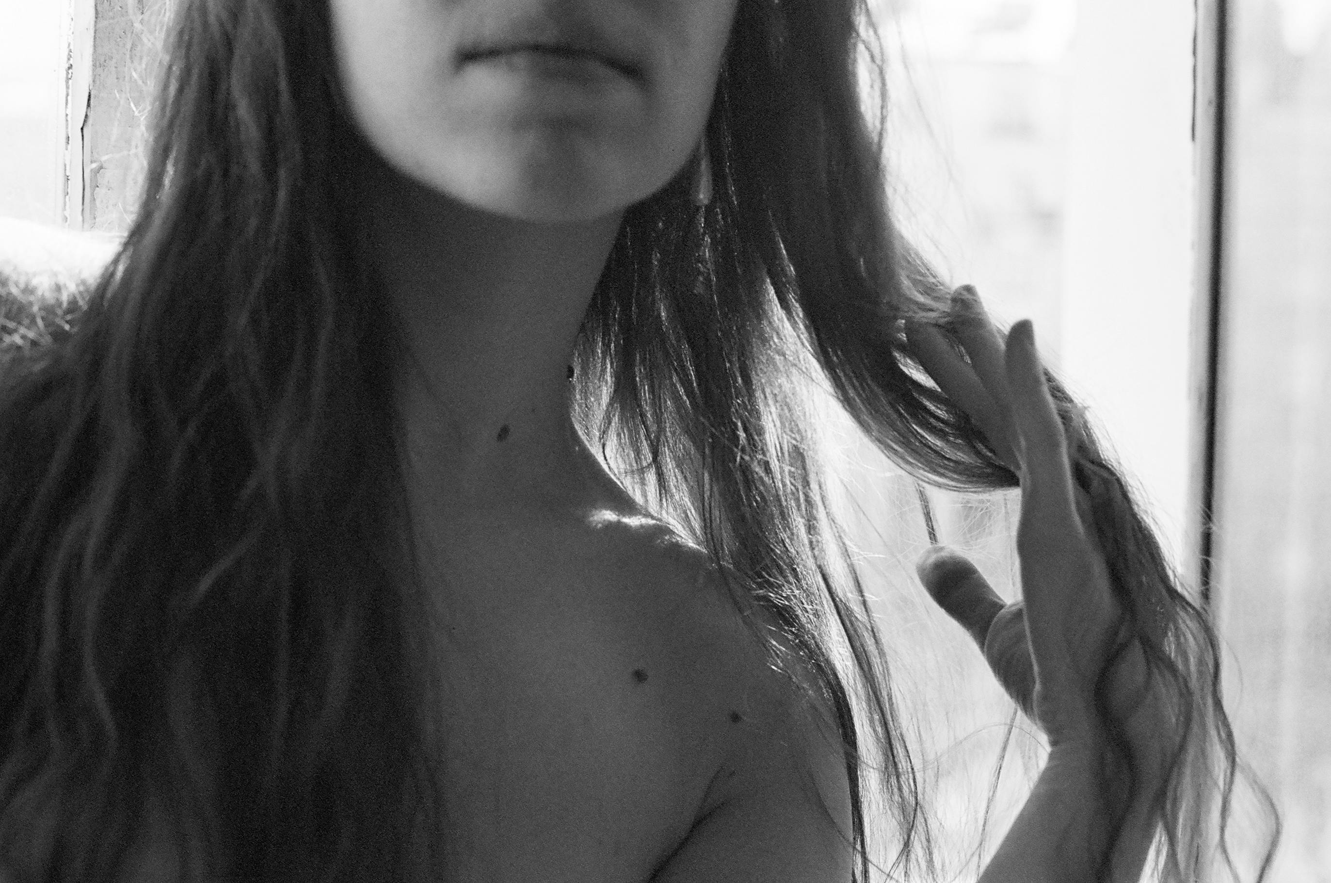 Artistic black and white portrait focusing on a woman's bare shoulder and flowing hair.
