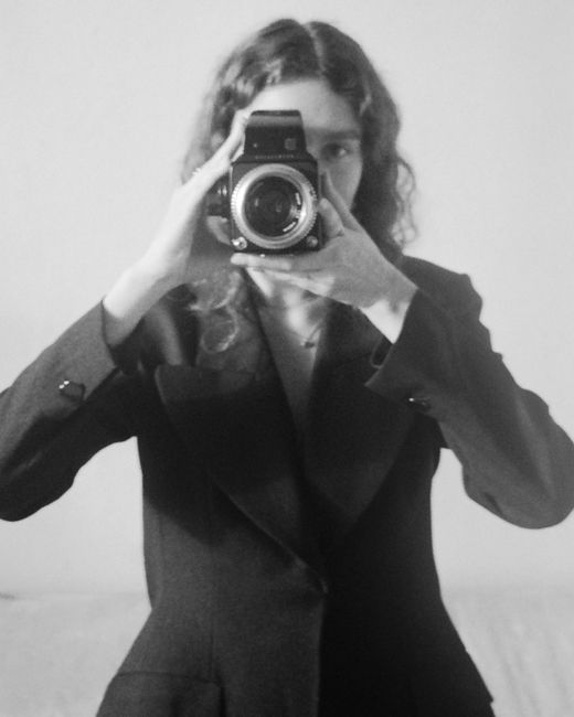 Black and white portrait of a woman holding a vintage camera, capturing a timeless feel.