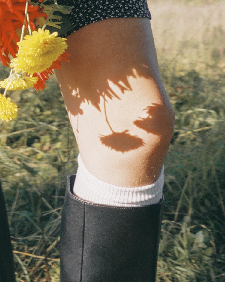 A Person Wearing A Knee Sock Holding A Flower