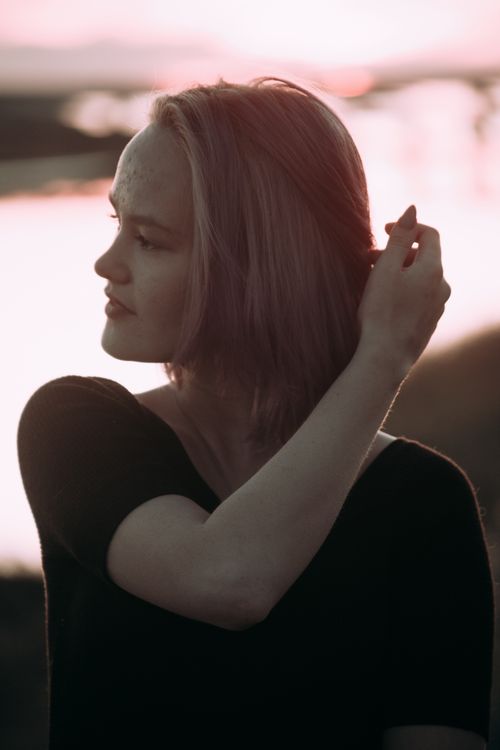 Free Profile view of a woman fixing her hair at sunset, creating a serene and peaceful mood. Stock Photo