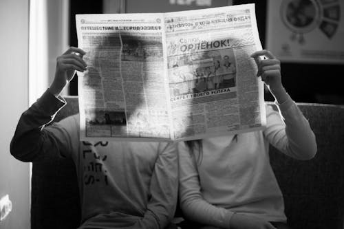 A Couple Backlit While Holding a Newspaper