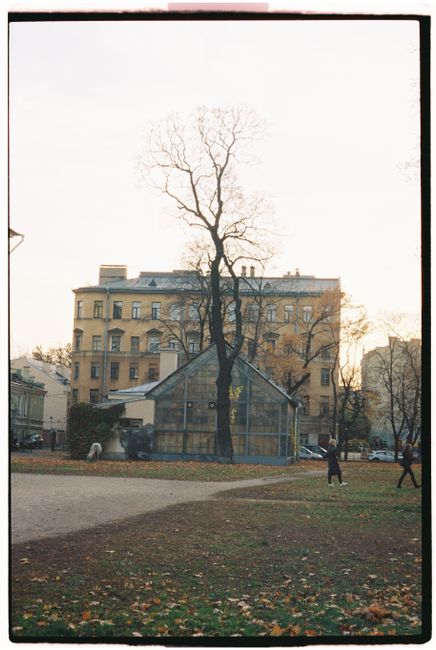 A serene urban park scene featuring historic buildings and walking paths in autumn.