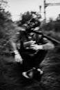 Blurred Shot of a Man Sitting on the Grassy Ground while Wearing Gas Mask
