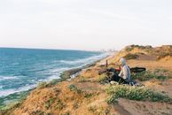 Man and Woman Sitting on Grass Field Near Body of Water