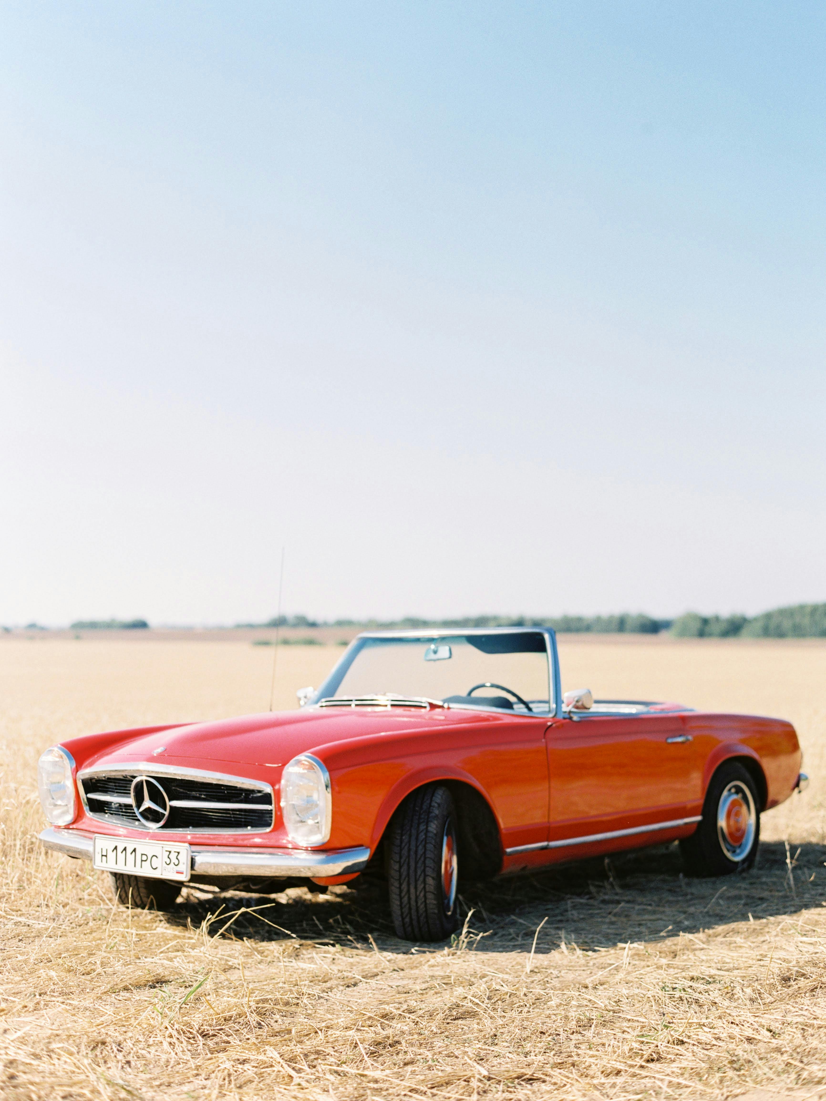 a red mercedes benz coupe in a field