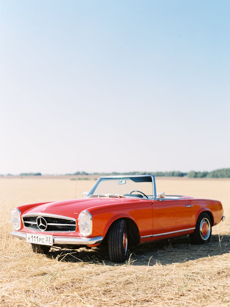 A Red Mercedes Benz Coupe In A Field 