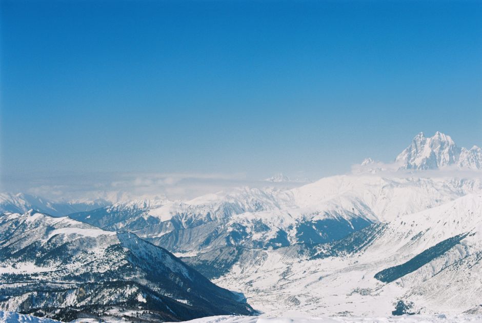 Breathtaking aerial photo of majestic snowy mountains under a clear blue sky.