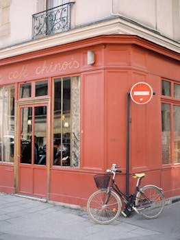 A vintage bicycle parked outside a quaint urban cafe with a red facade.