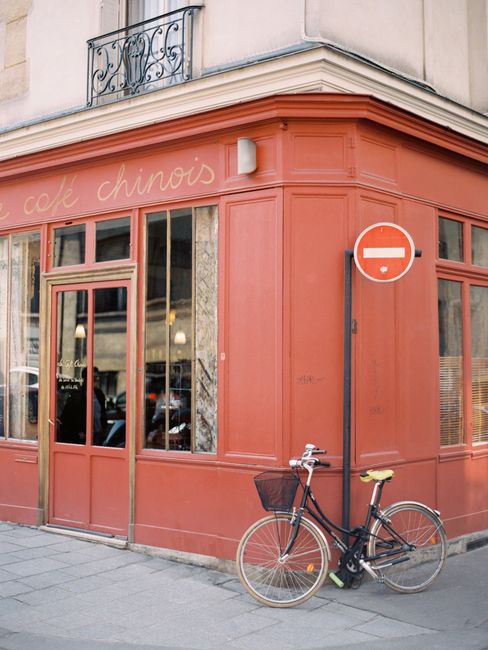 A vintage bicycle parked outside a quaint urban cafe with a red facade.