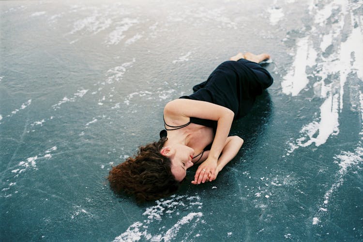 Woman Lying On Frozen Body Of Water 