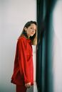 Woman in Red Long Sleeve Shirt Standing Beside Black Curtain