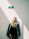 Woman in Black Leather Jacket Standing Near White Wall