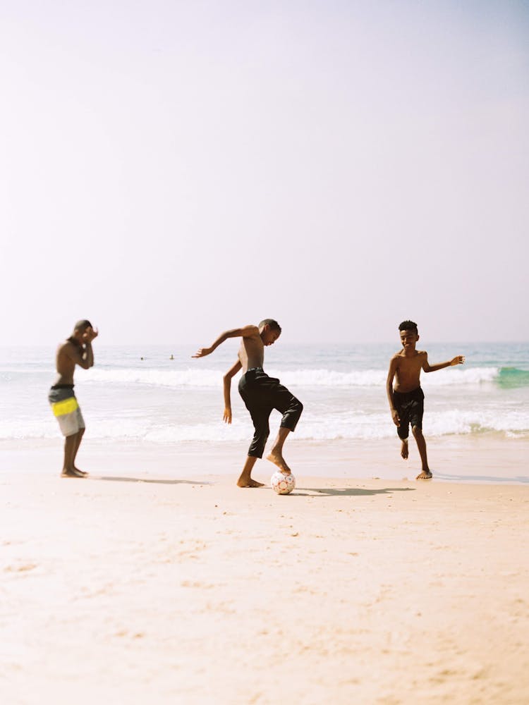 Kids Playing Ball On The Shore Of The Beach