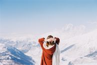 Person in Brown Scarf Standing on White Snow Covered Mountain