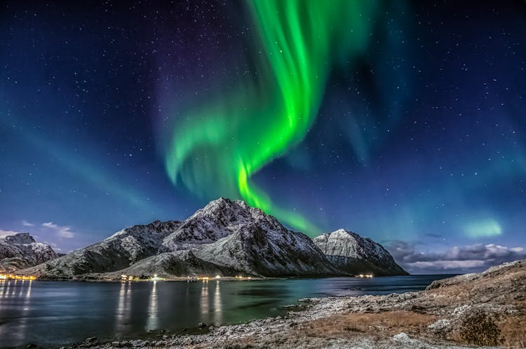 Green Aurora Borealis Over Snow Covered Mountain