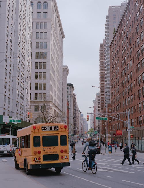 Yellow School Bus Traveling the Road Near High Rise Buildings