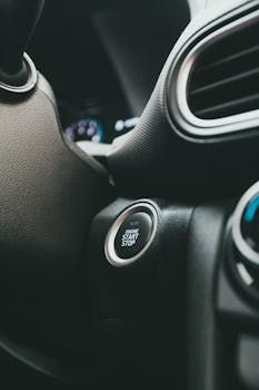 Close-up of a car's start-stop button and dashboard, showcasing modern automotive technology.