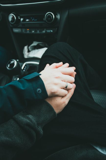 Close-up of couple holding hands in a car, symbolizing love and togetherness.