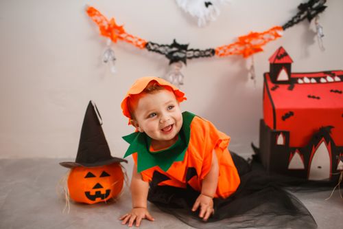 Free Cute baby in a pumpkin costume enjoying a Halloween-themed setting with decorations. Stock Photo
