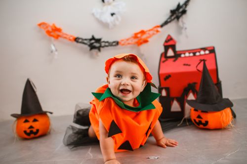 Free Cute baby dressed as a pumpkin, enjoying Halloween with decorations. Stock Photo