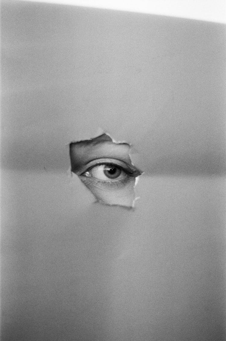 Eye Looking Through A Hole In Paper 