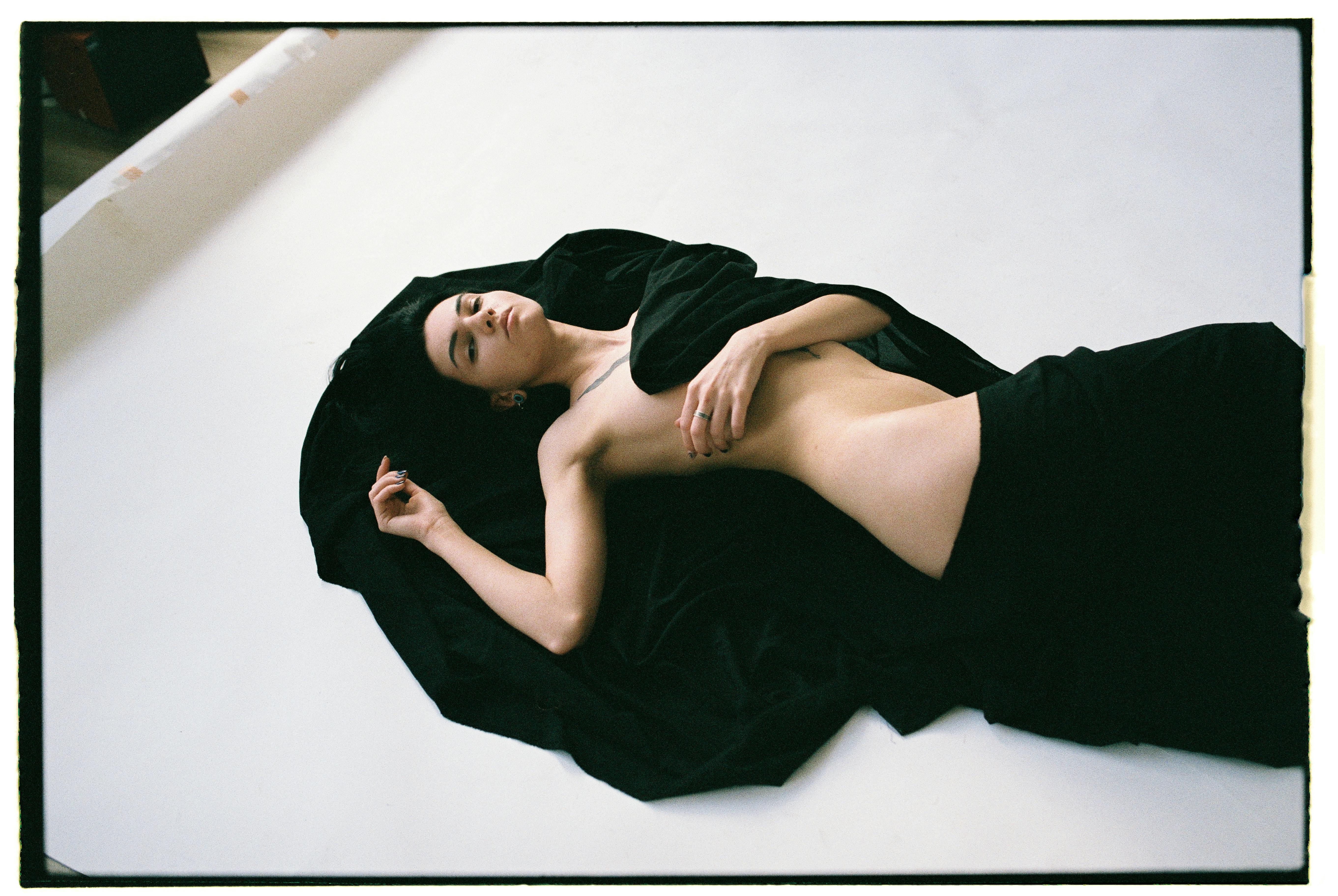 Artistic photo of a woman posing gracefully on black velvet fabric indoors.