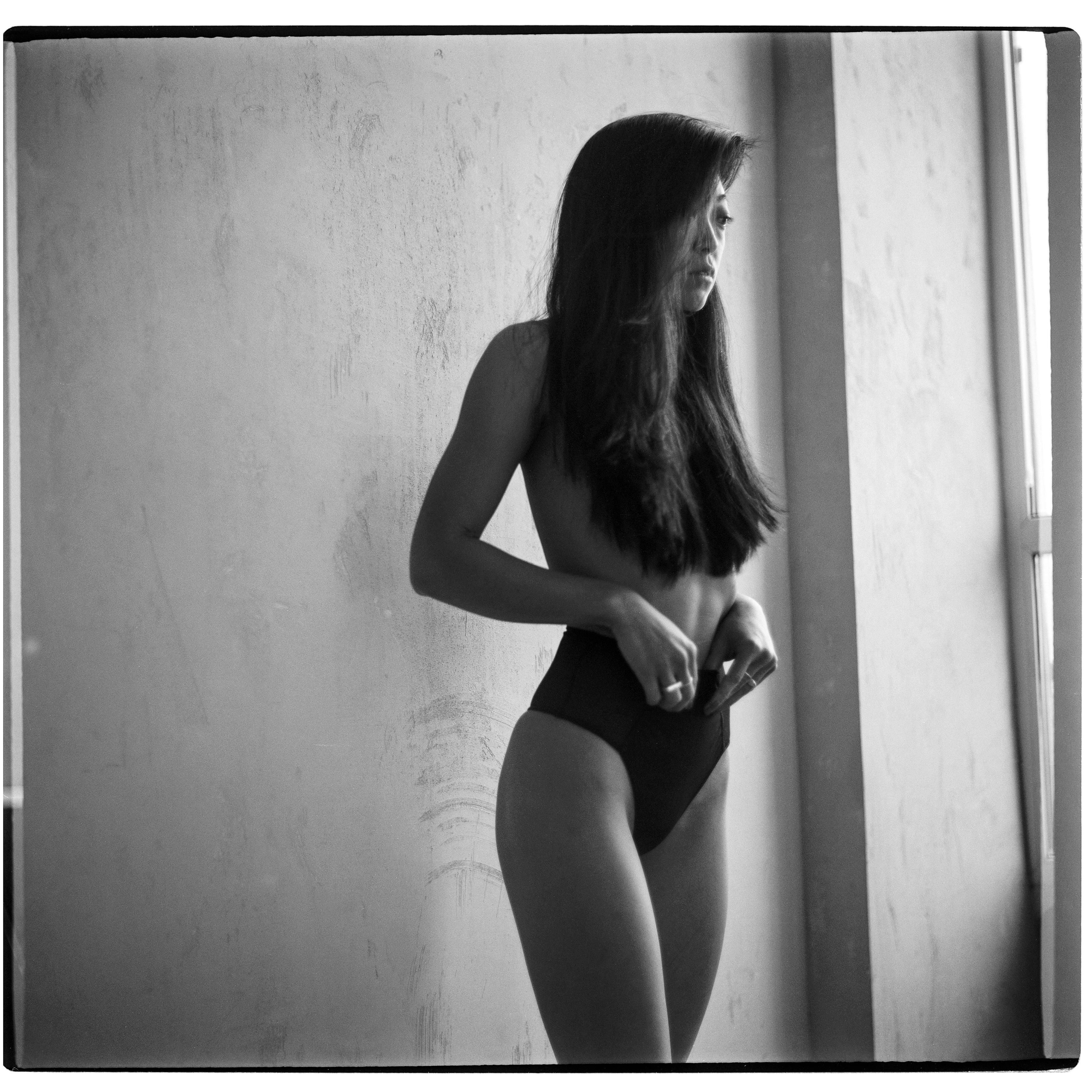 Elegant monochrome image of a woman in an artistic pose by a window.