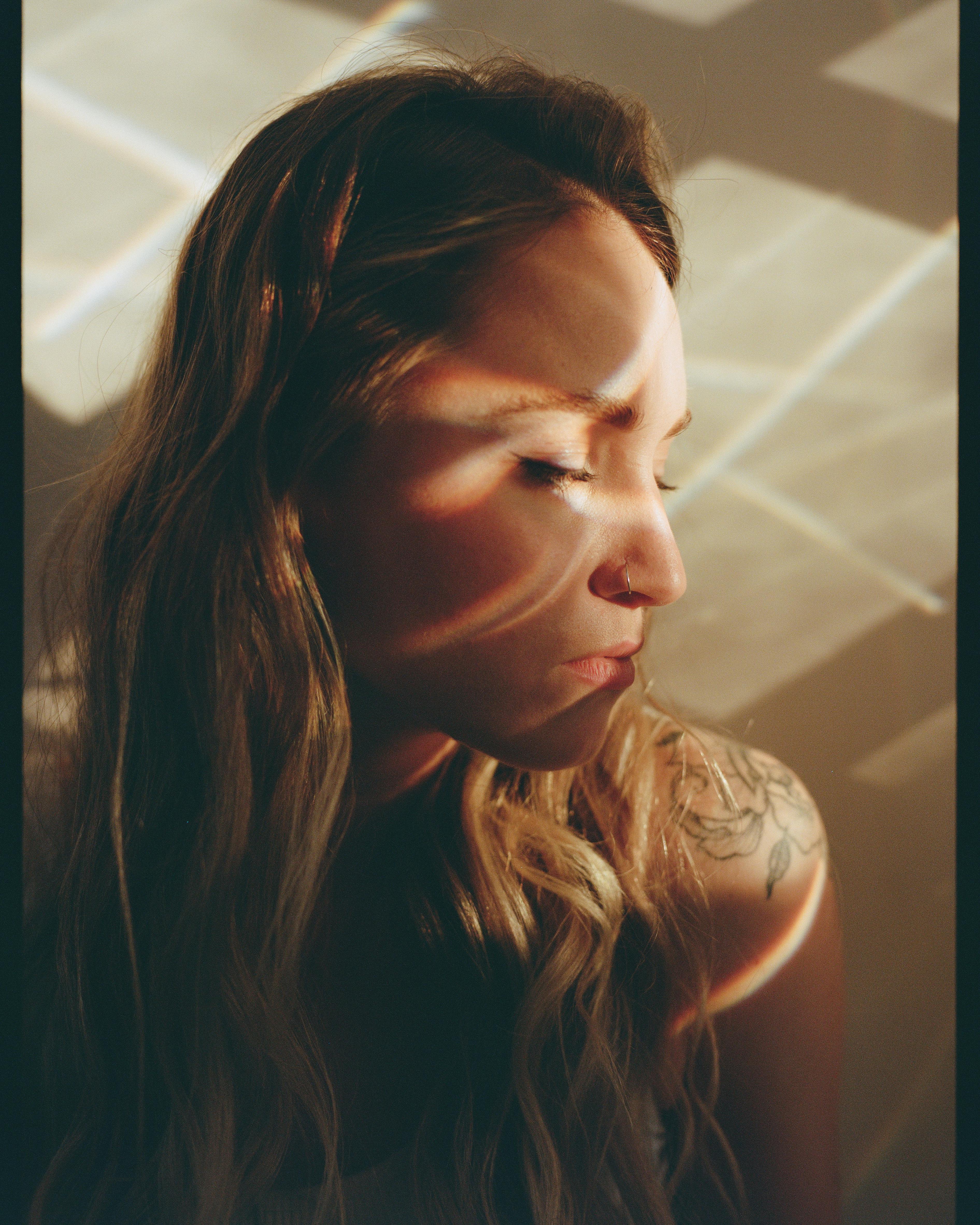 Close-up artistic portrait of a woman with sunlit patterns on her face, Moscow.