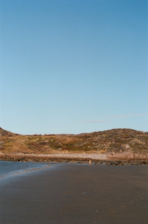 Foto profissional grátis de beira mar, céu azul, colinas