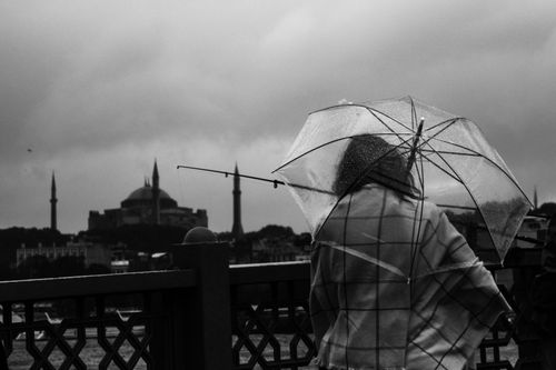 Free A woman with umbrella gazing at the iconic Hagia Sophia in a rainy, monochrome Istanbul. Stock Photo
