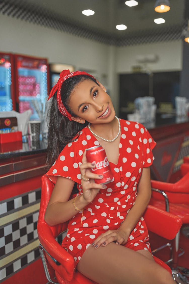 A Woman In A Red Polka Dot Dress Holding A Coke Can  