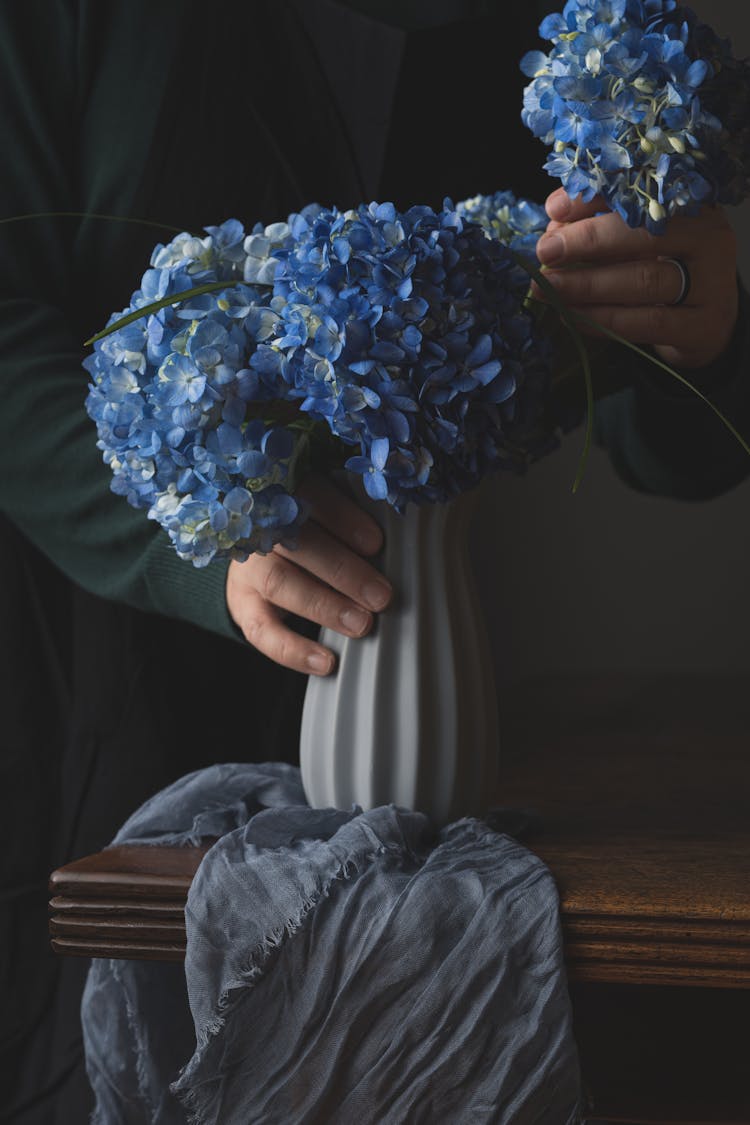 Photo Of A Person's Hands Arranging Blue Hydrangea Flowers