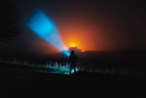 Free A mysterious silhouette stands in a foggy field with vibrant lights and a moody atmosphere. Stock Photo