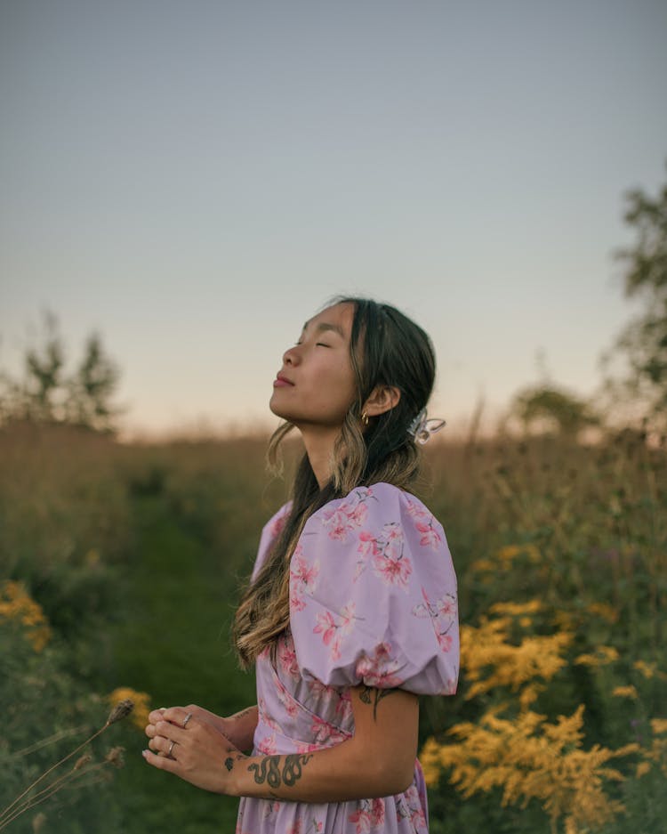 Woman Standing In Field At Sunset