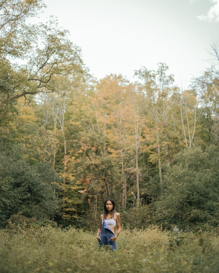 Woman In Dungarees Against Autumn Forest