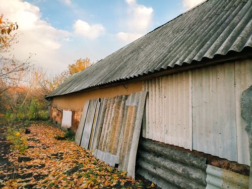 Free Rustic building with rusted metal cladding and fallen leaves in autumn setting. Stock Photo