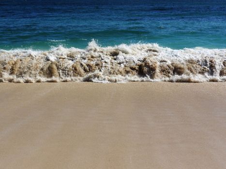 Vivid waves rolling onto a sunlit sandy beach, capturing the essence of a serene seaside.