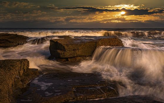 Stunning seascape with dramatic waves and rocks at sunset, capturing nature's power and beauty.