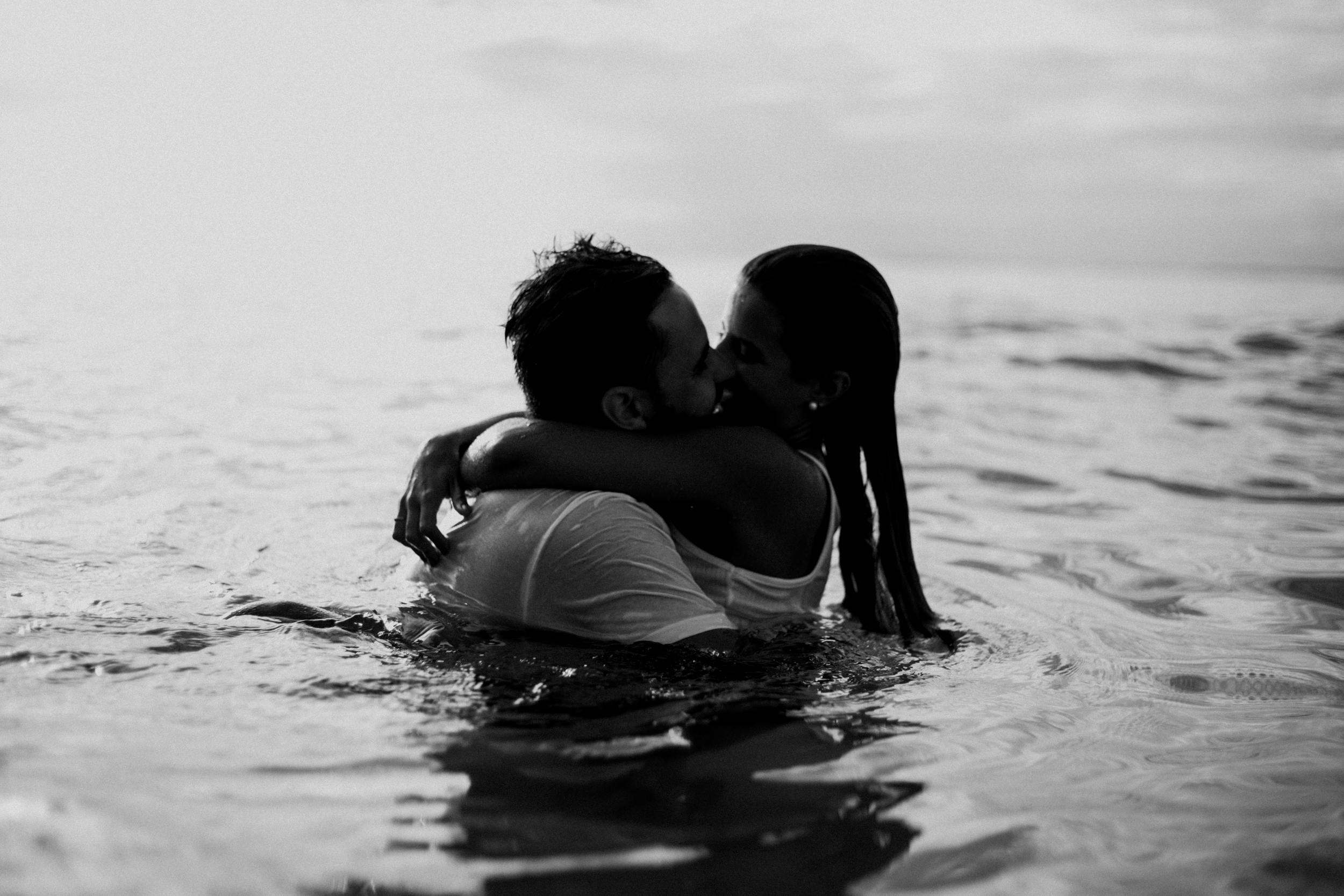 man and woman kissing together on body of water