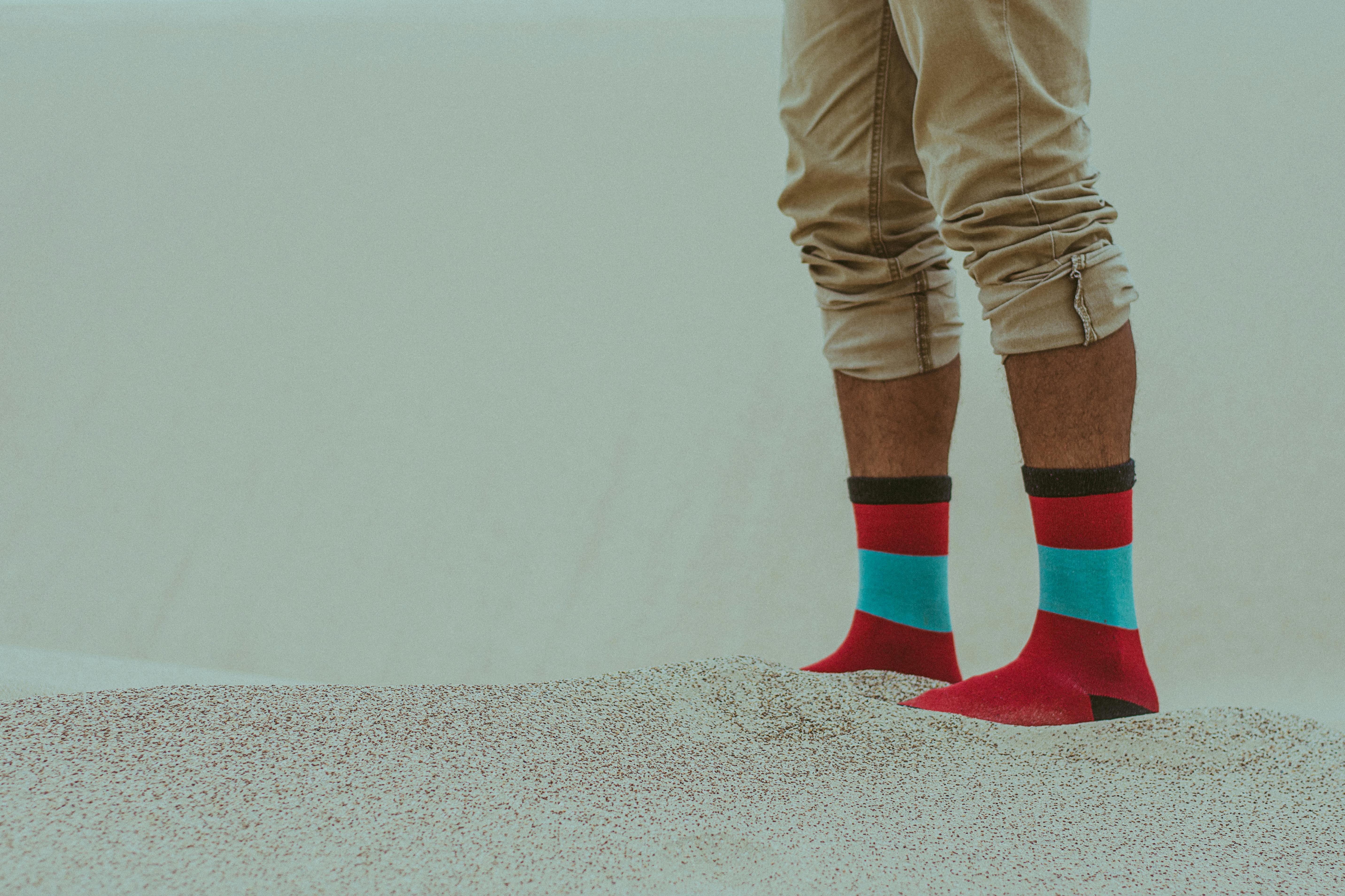person wearing red socks standing on sand