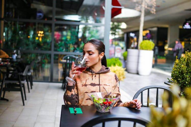 Woman Drinking Red Wine At Restaurant Table