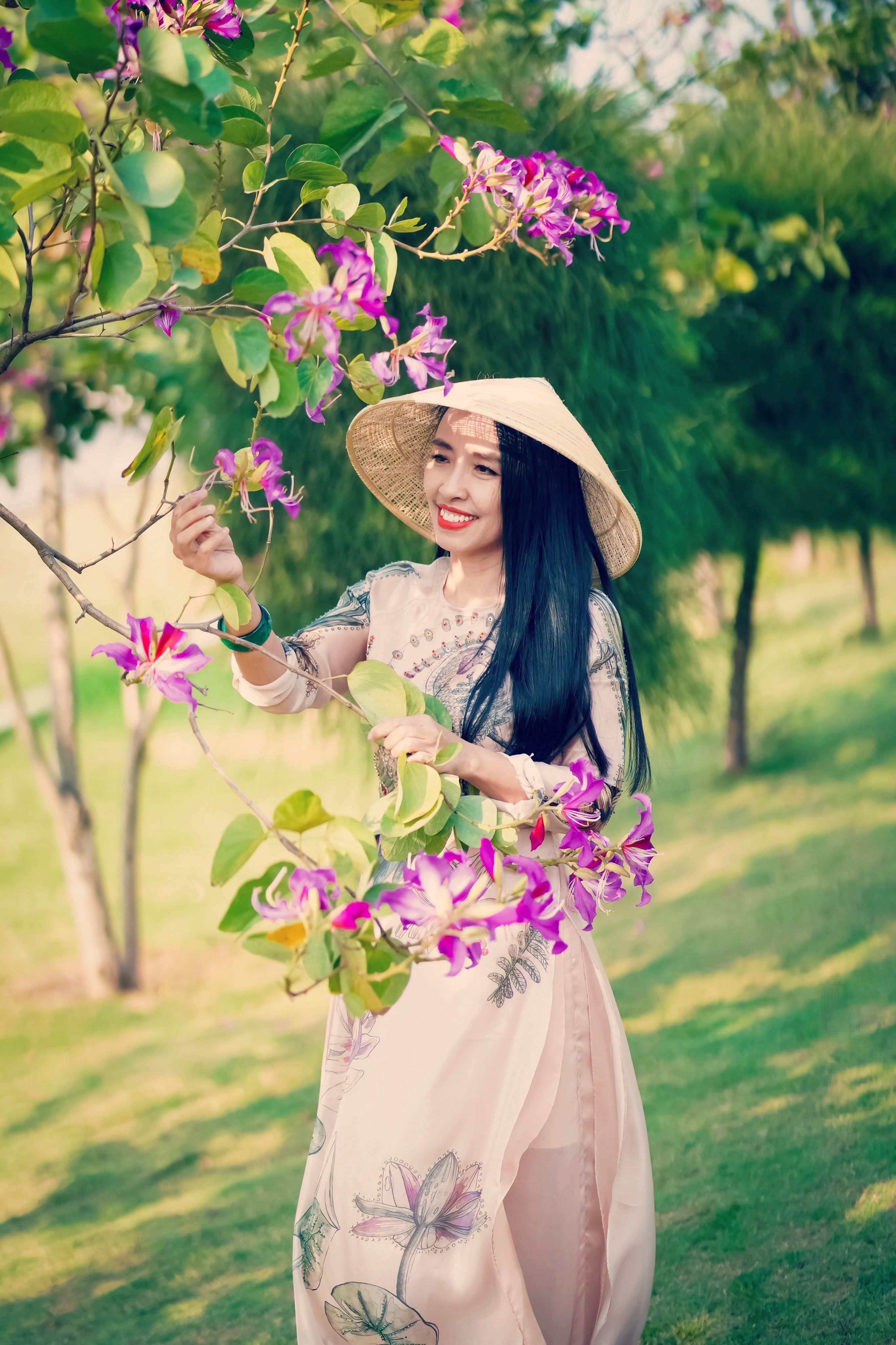 A Woman Wearing Floral Dress and a Straw Hat Holding Flowers from the ...