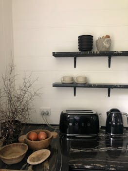 Stylish kitchen setup with black toaster, kettle, and rustic decor.