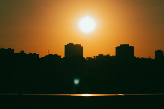 Silhouette of city buildings under a vibrant sunset sky, creating a dramatic urban skyline.