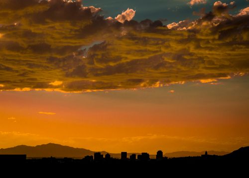 Free Captivating silhouette of Salt Lake City against a vibrant orange sunset with dramatic clouds. Stock Photo