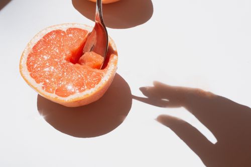 Free Freshly sliced grapefruit with a spoon highlighting its juicy texture and bright sunlight. Stock Photo